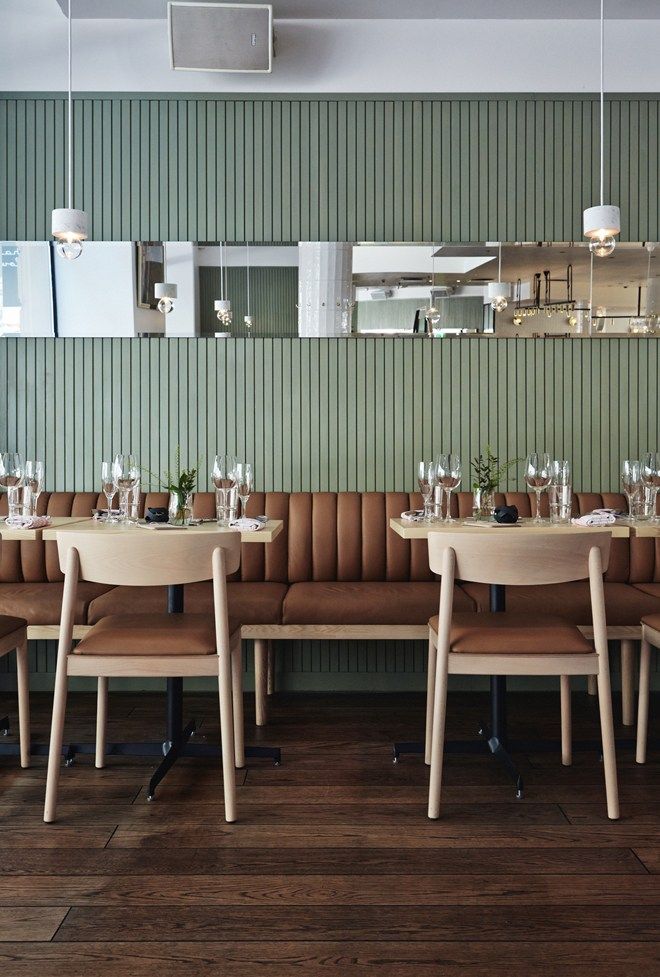 an empty restaurant with tables and chairs in front of a wall that has green vertical stripes on it