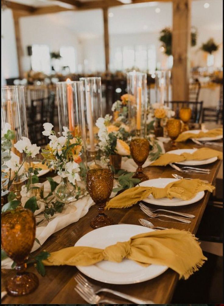 the table is set with plates, silverware and yellow napkins as well as flowers