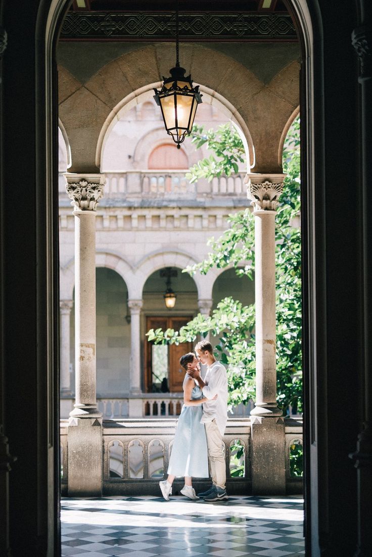 two people standing under an archway in the middle of a building, one holding his arm around the other's neck