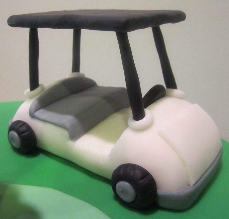 a cake shaped like a toy car on top of a green tablecloth with white and black icing