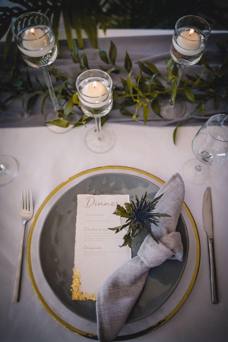 a place setting with napkins, silverware and candles on the table for an elegant dinner