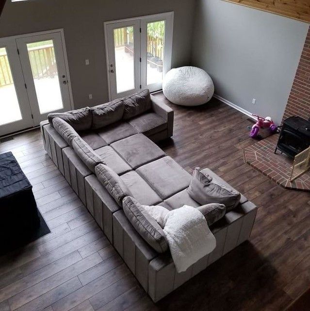 an overhead view of a living room with couches and pillows on the hardwood floor