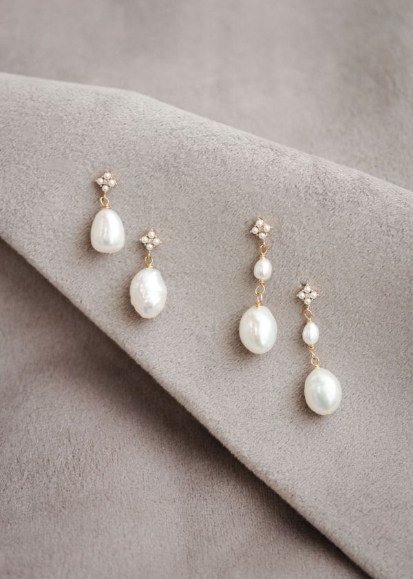 three pairs of pearl and diamond earrings sitting on top of a gray cloth with a white background