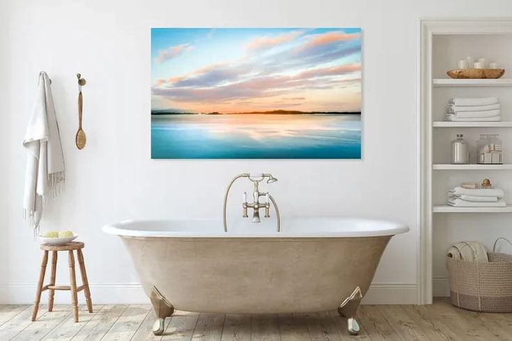 a bath tub sitting next to a white wall with a painting on the wall above it