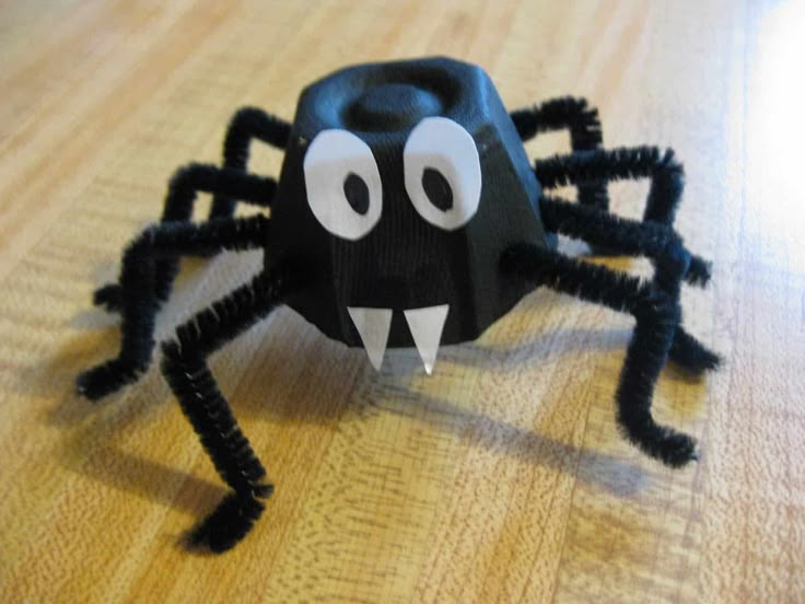 a black paper spider sitting on top of a wooden table