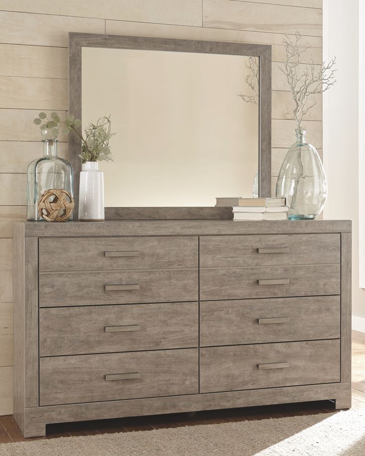 a dresser with a mirror and vases on it