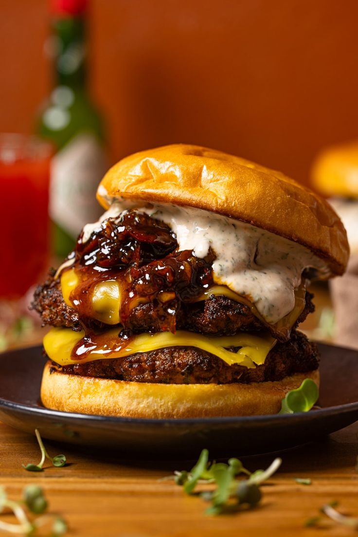 a burger with meat, cheese and sauce on a black plate