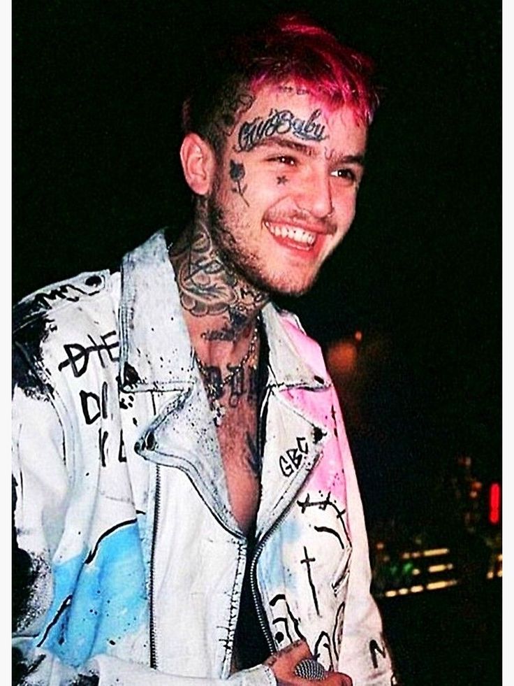 a man with pink hair and tattoos on his face smiles at the camera while wearing a white jacket