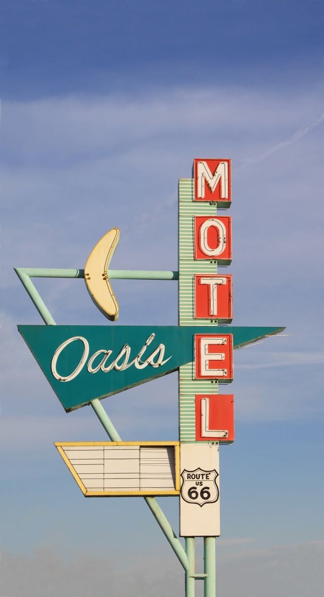 a motel sign with the word oasis on it's side and a banana hanging from the top