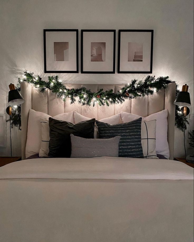 a white bed topped with lots of pillows and christmas decorations next to two framed pictures