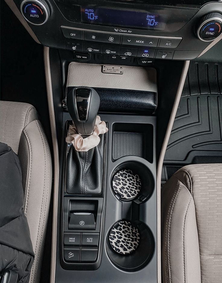 the interior of a car with an automatic gear box and cup holders in it's center console