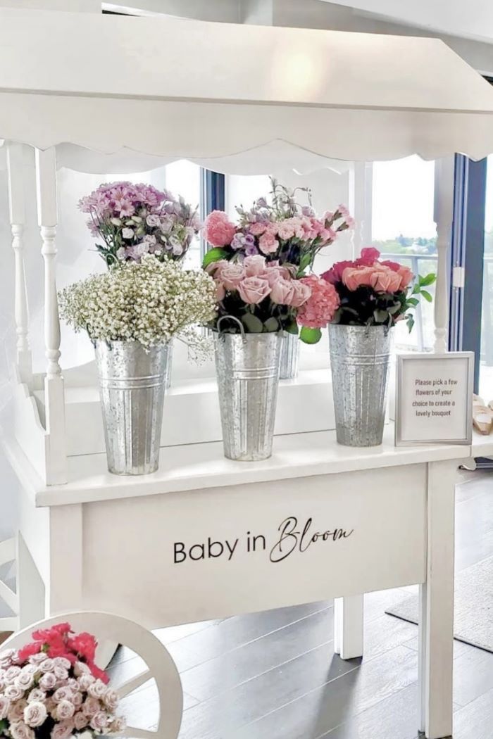 three buckets filled with flowers sitting on top of a white bench next to a window