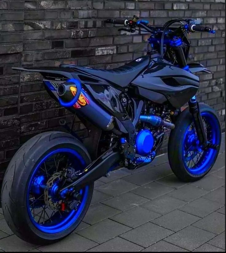 a black and blue motorcycle parked next to a brick wall