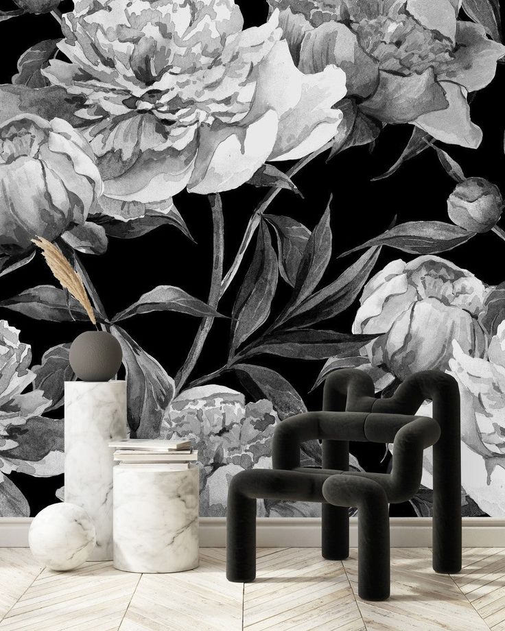 a black and white floral wallpaper with large flowers on the back ground, next to two stools