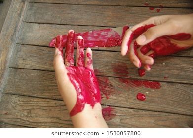 two hands are covered in red paint on a wooden table