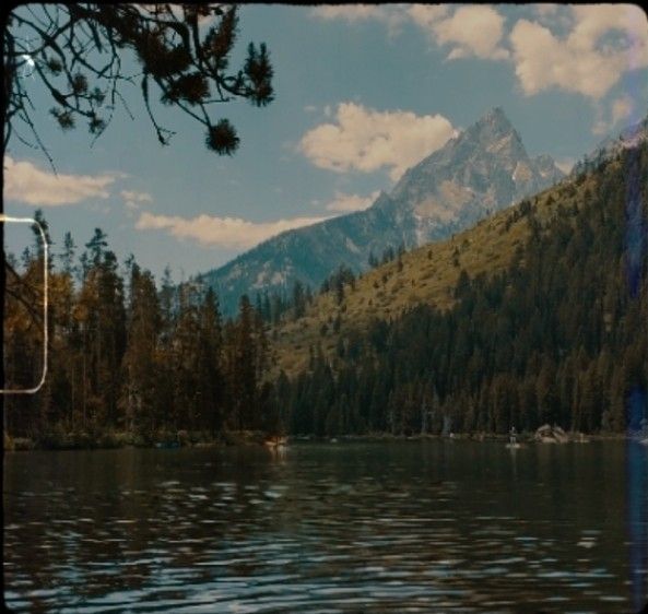 a lake surrounded by trees and mountains under a cloudy sky