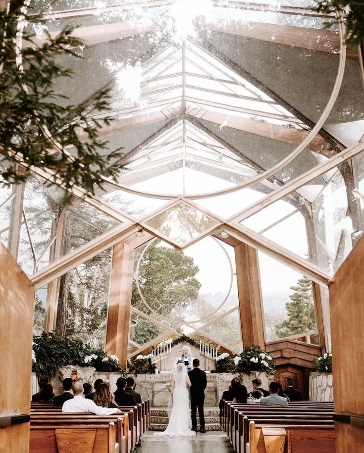 the bride and groom are standing in front of the alter at their wedding ceremony, surrounded by wooden pews