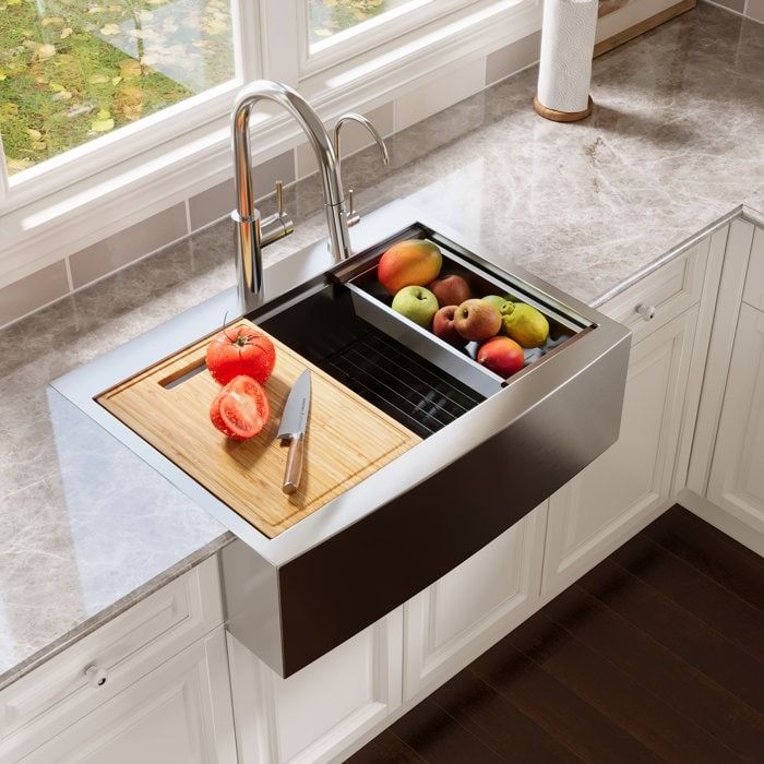 a stainless steel kitchen sink with cutting board and fruit