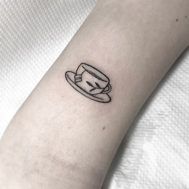 a small hat tattoo on the left inner arm, with an eyeball in it