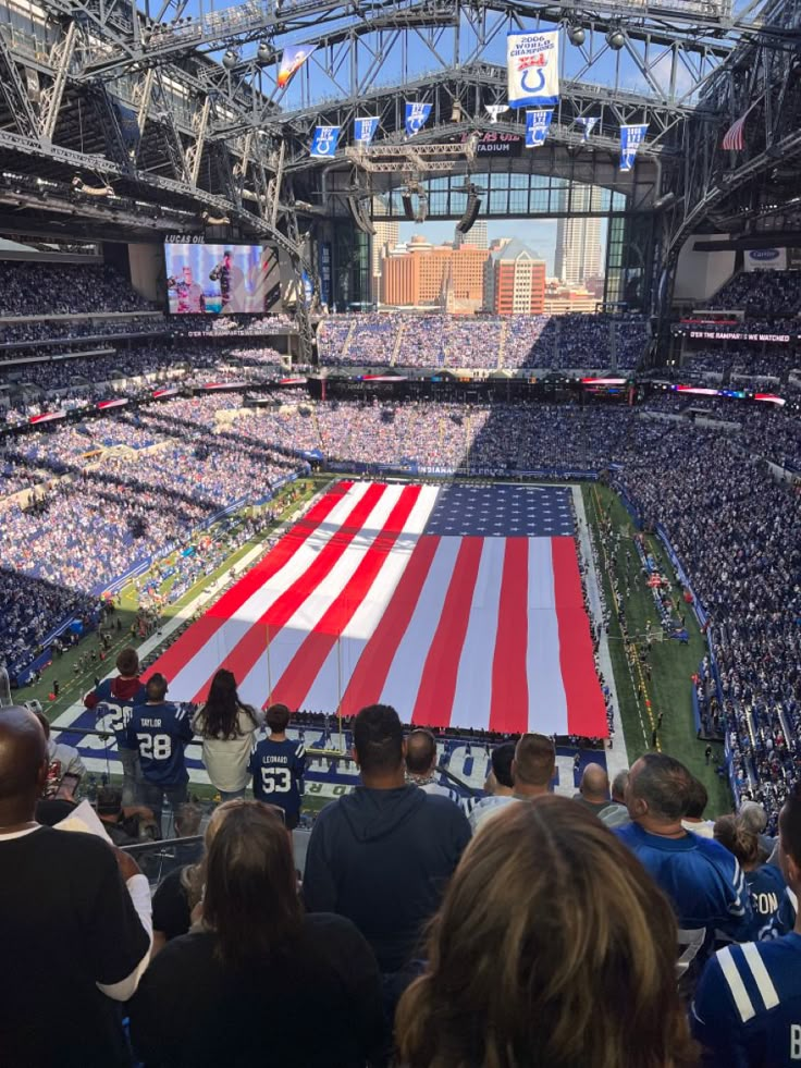 a large american flag is displayed in the middle of a football stadium as people watch