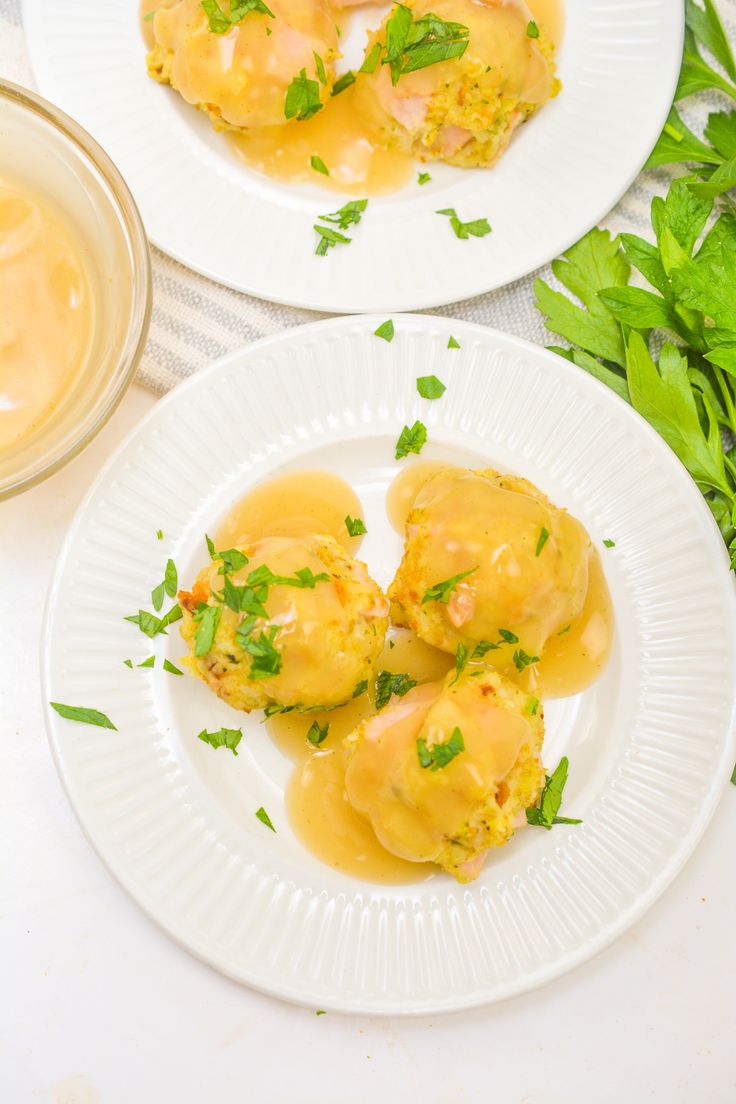 two white plates topped with ravioli covered in gravy and garnished with parsley