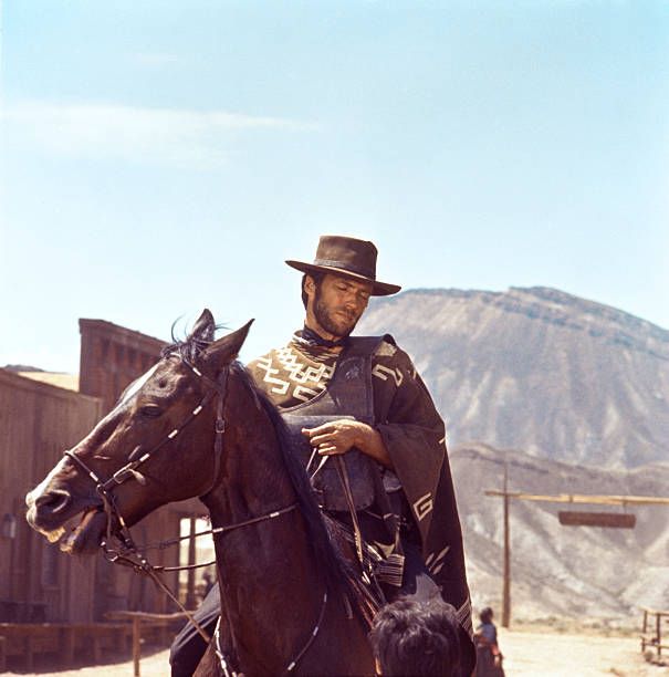 a man riding on the back of a brown horse wearing a cowboy hat and black jacket