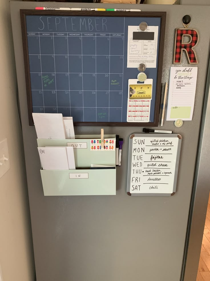 a refrigerator with magnets and papers attached to the door, next to a wall calendar