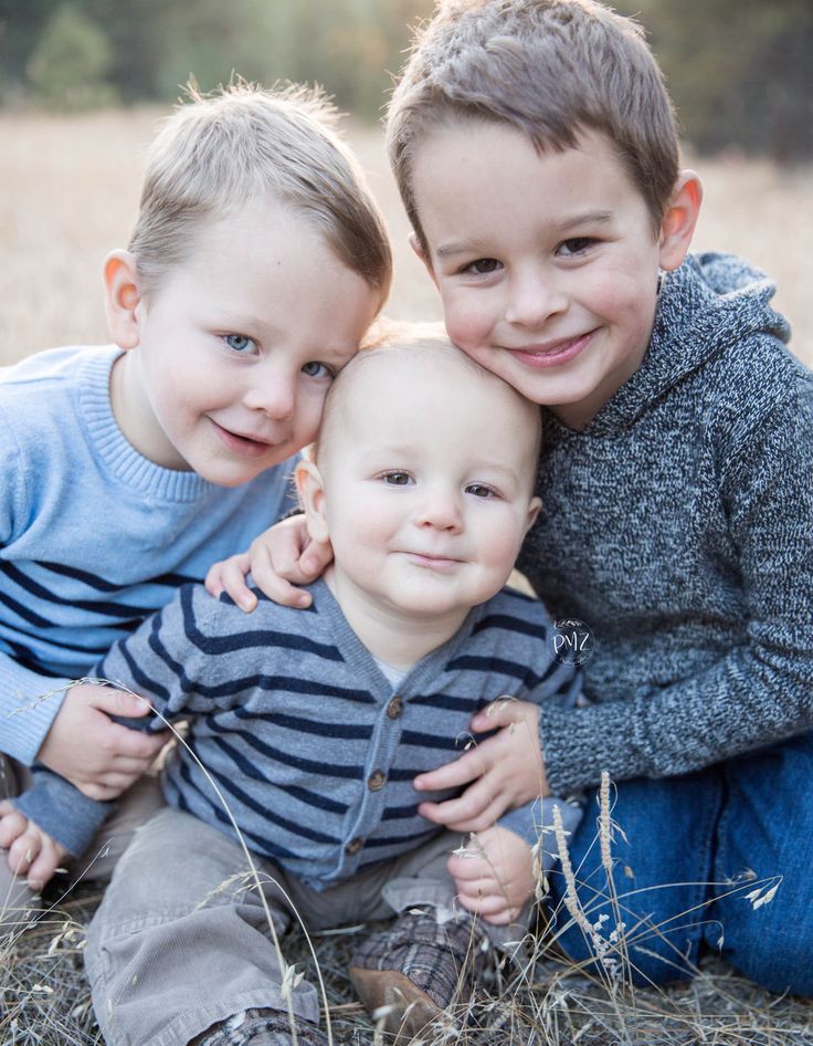 two young boys sitting on the ground with their arms around each other and smiling at the camera