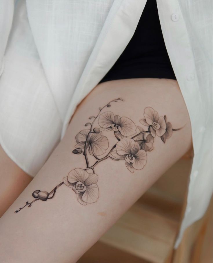 a woman's thigh with flowers on it and a branch in the middle of her leg