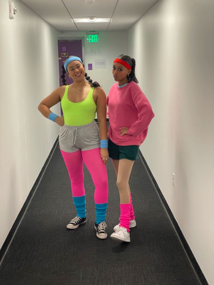 two women in neon colored clothing standing on a long hallway