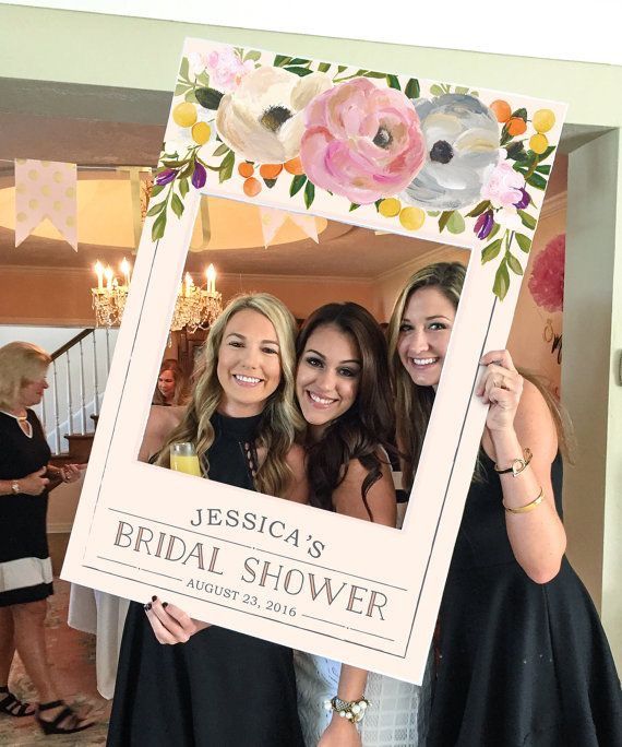 two women holding up a photo frame with flowers on it and the caption reads, wedding photo prop baby shower prop