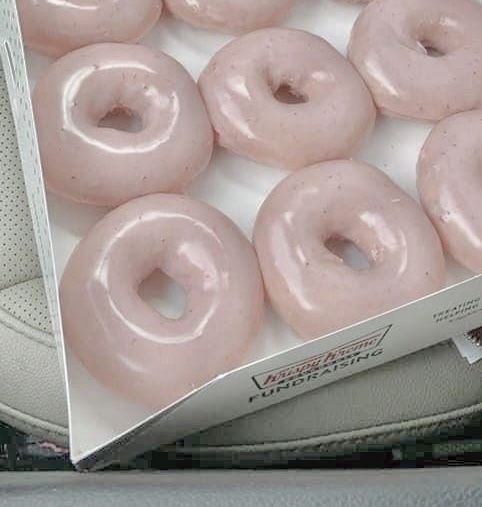 a box filled with pink donuts sitting on top of a car seat