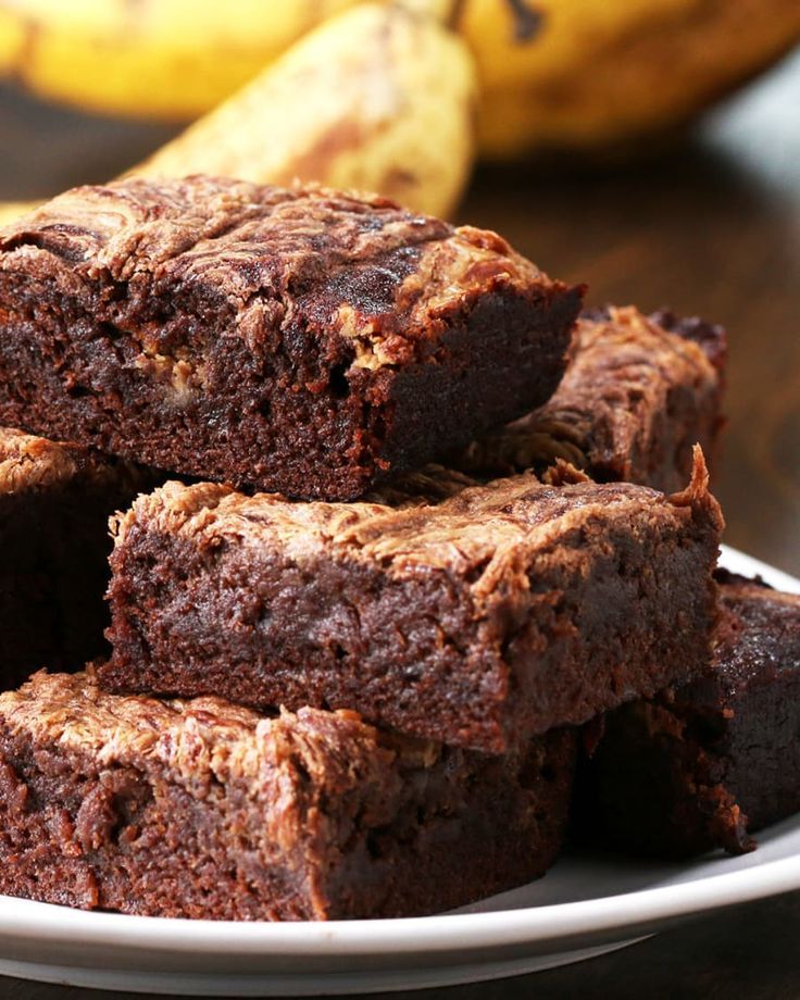 some brownies are stacked on top of each other in front of banana's