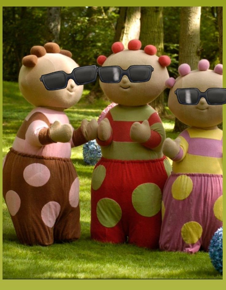 three inflatable characters are standing on the grass with their arms around each other