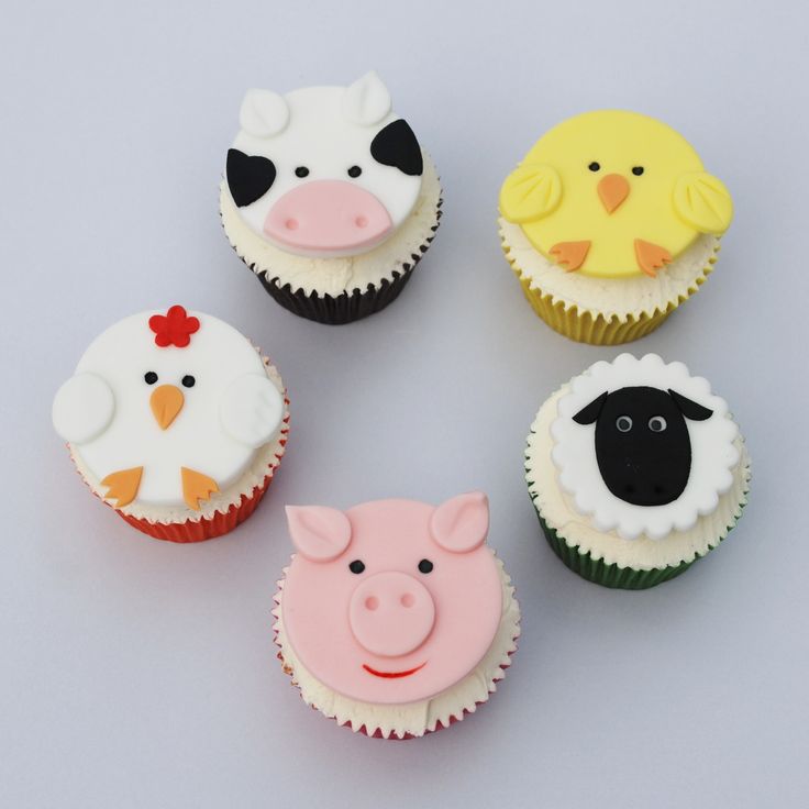 four cupcakes with farm animals and sheep on them