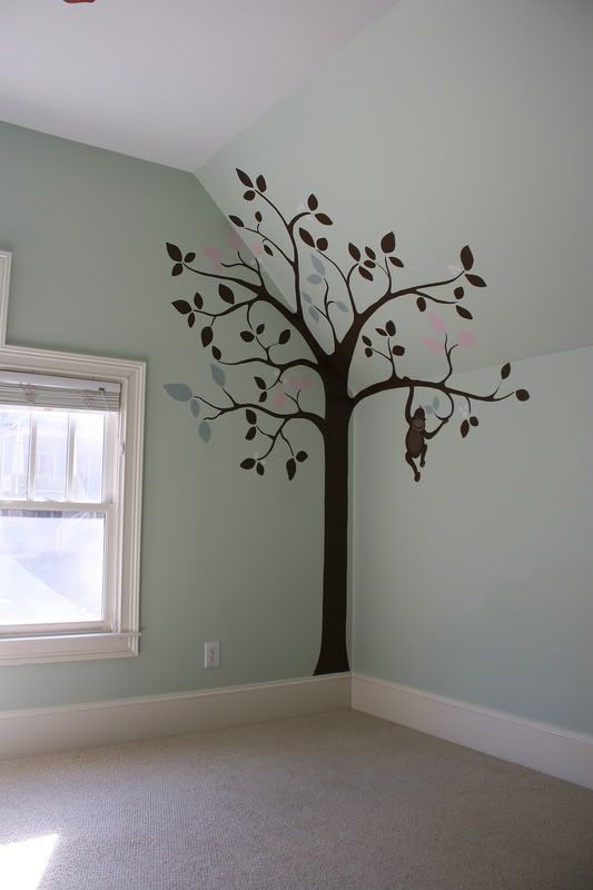 an empty room with a tree painted on the wall and a window in the corner