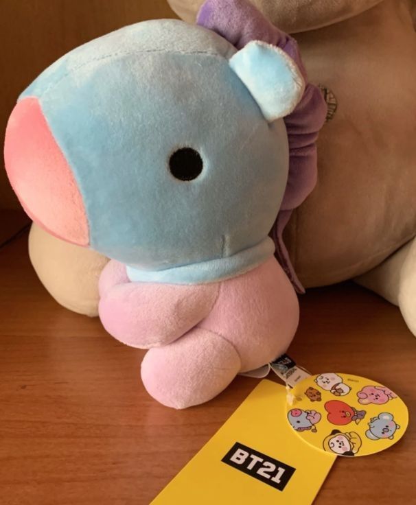 two stuffed animals sitting next to each other on a wooden table with a yellow tag