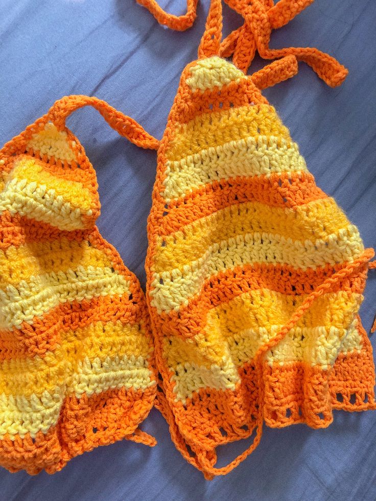 an orange and yellow crocheted bag laying on top of a bed