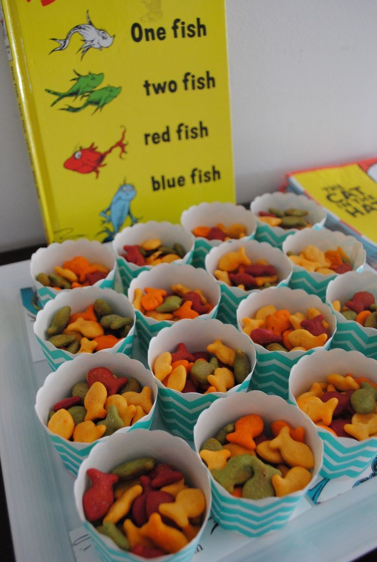 there are many small cups that have fish in them on the table next to a book