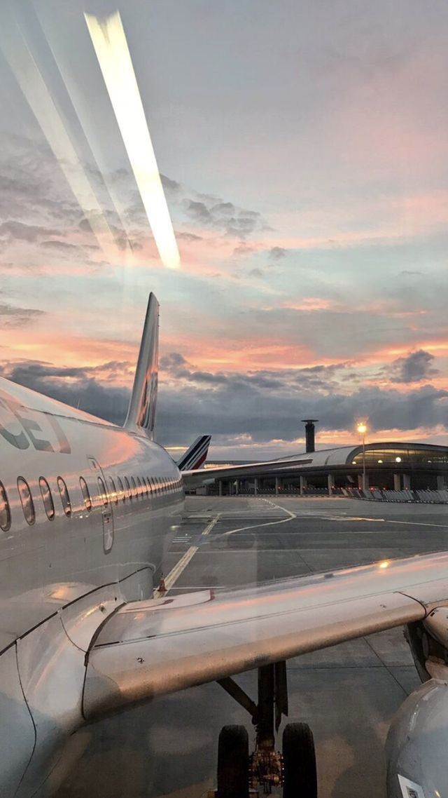 an airplane is sitting on the tarmac at sunset with a frame in front of it