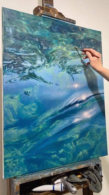 a person is painting on an easel with blue water