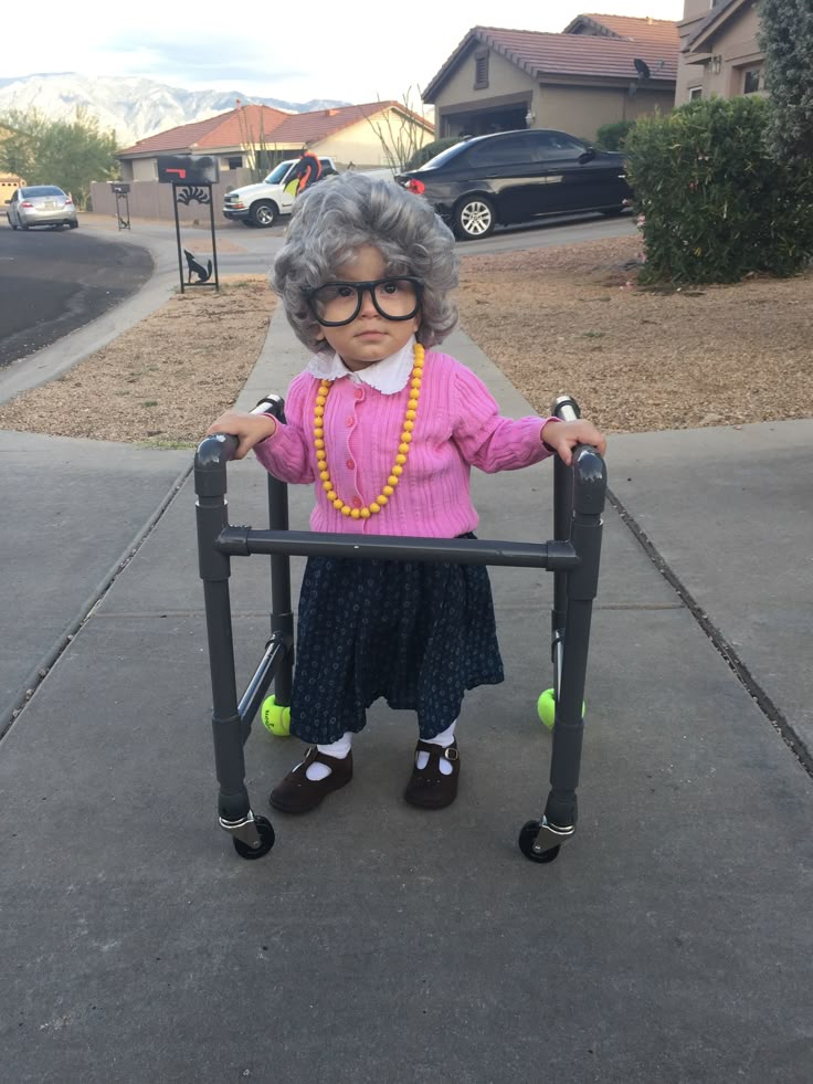 an old woman in glasses and a pink sweater is standing on a black metal frame