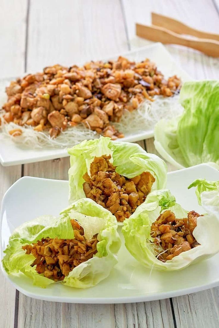 lettuce wraps filled with meat and garnishes on a white plate