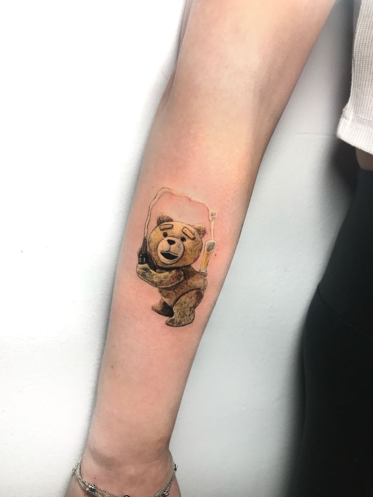 a small bear tattoo on the arm