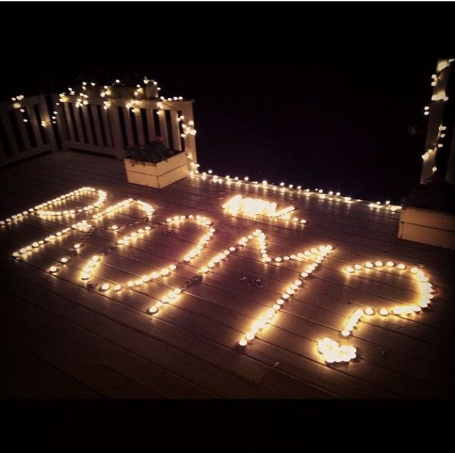 the word love spelled out with lights on top of a wooden deck in front of a gazebo