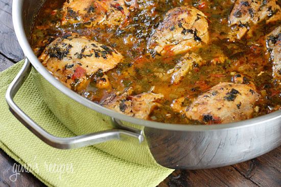 a pot filled with meat and sauce on top of a wooden table next to a green towel