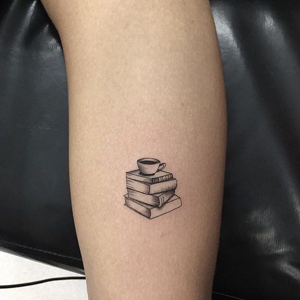 a black and white photo of a tattoo on the leg of a person with a stack of books