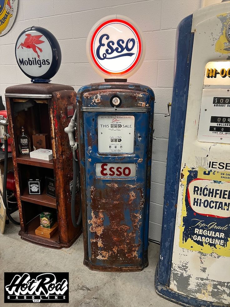 two old gas pumps are next to each other in a room with signs on the wall