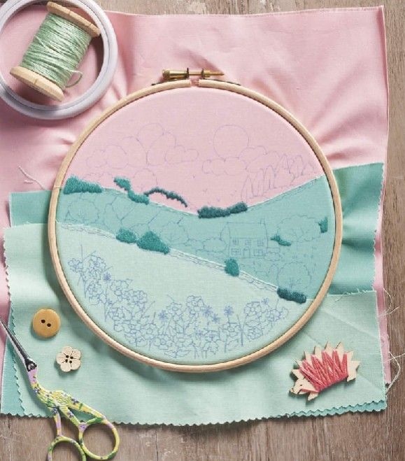 an embroidery project with scissors, thread and spools on a pink cloth next to a pair of scissors