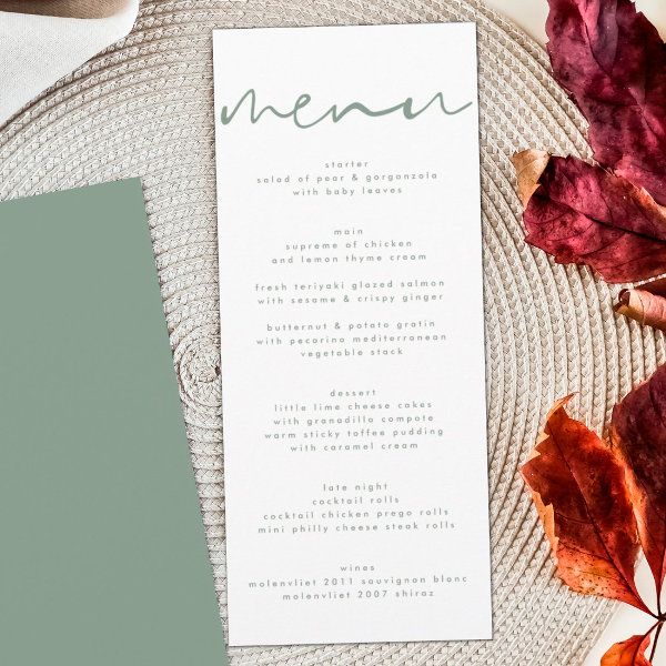 a menu card sitting on top of a table next to some leaves and a cup